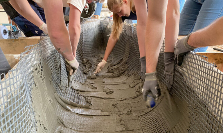 Hände streichen Beton auf Kanudrahtgerüst