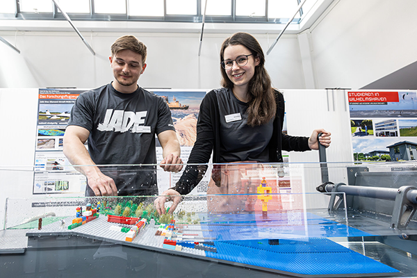 Sebastian Neikes und Nicole Bratz studieren an der Jade Hochschule im Bachelorstudiengang Meerestechnik. Sie lernen und forschen, wie in Zukunft mit Hilfe von Technologien der Küstenschutz verbessert werden kann. Auf dem Jade Campustag in Oldenburg konnten die Besucher an einem Demonstrationsmodell verschiedene Szenarien nachvollziehen. (Foto: Jade HS/Andreas Rothaus)