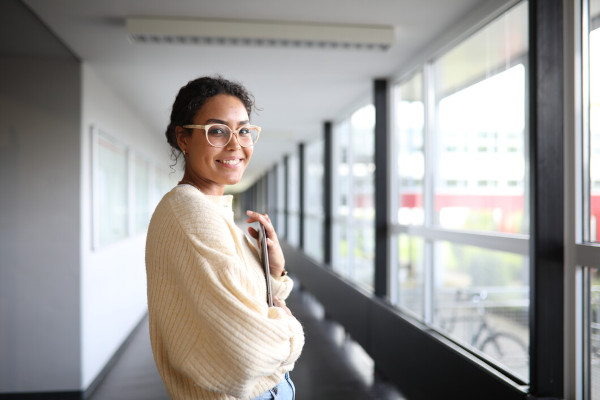 Lehr- und Lernzentrum (LQ) Studierende steht lächelnd im Flur des Hochschulgebäudes
